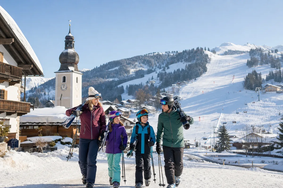 Familie auf dem Weg zur Piste in einem österreichischen Alpendorf