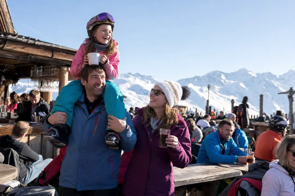 Vater trägt seine Tochter auf den Schultern auf einer sonnigen Terrasse in den Alpen